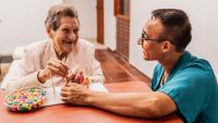 Caregiver and senior woman playing with abaco toy
